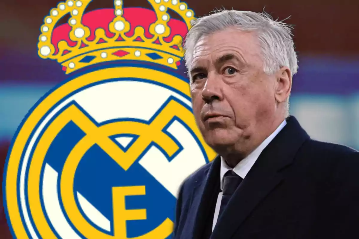 Un hombre de cabello canoso con traje oscuro está frente a un escudo de un equipo de fútbol.