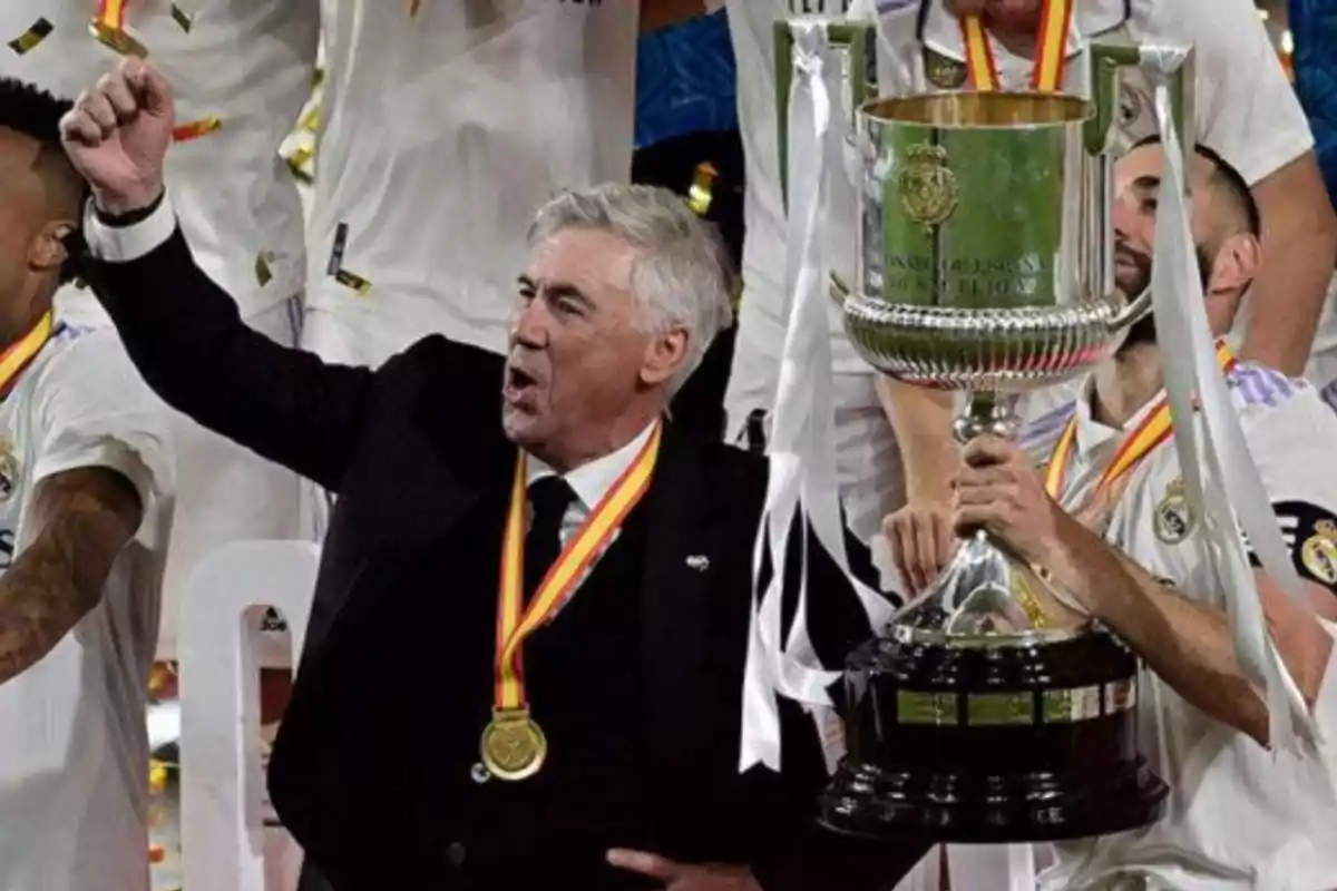 A soccer coach enthusiastically celebrates as a player holds a large trophy surrounded by teammates with medals. A soccer coach enthusiastically celebrates as a player holds a large trophy surrounded by teammates with medals.