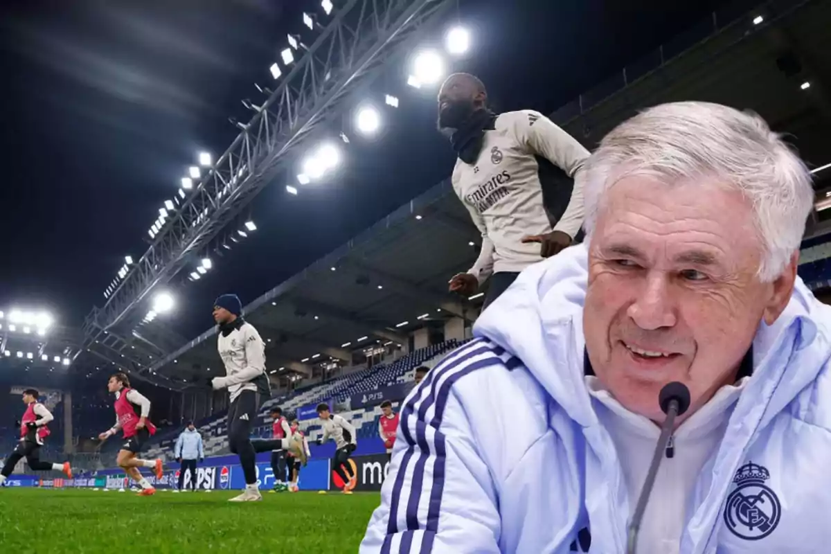 A soccer team training in a floodlit stadium with a smiling coach in the foreground.