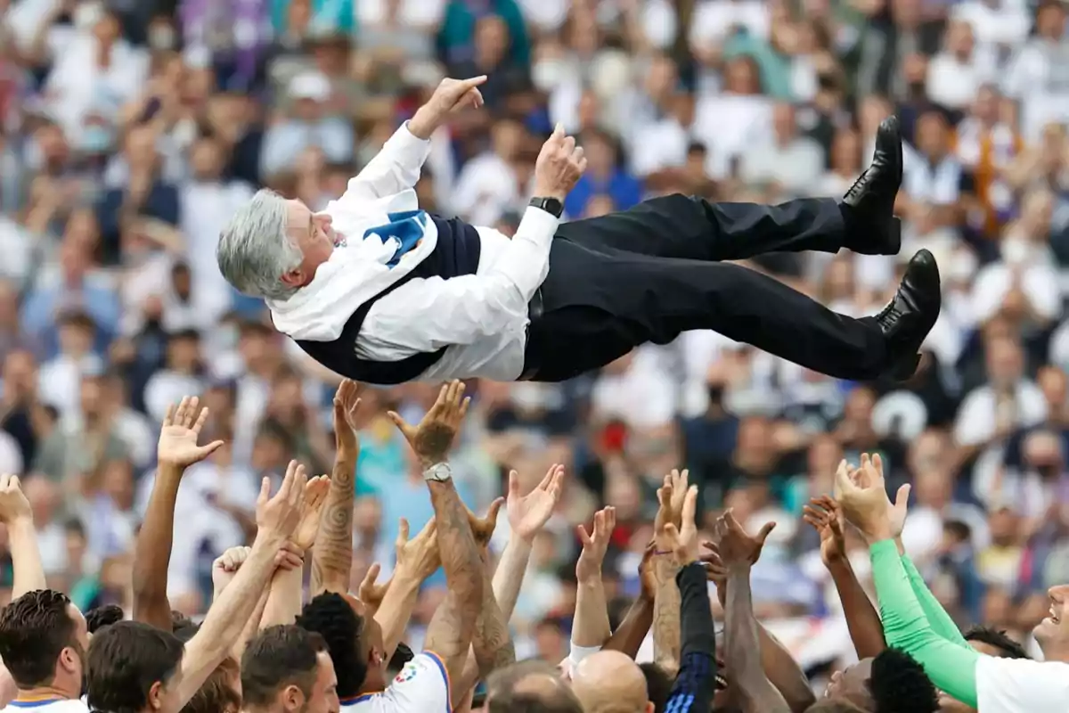A group of people throw a man dressed in a suit into the air in a stadium full of spectators. A group of people throw a man dressed in a suit into the air in a stadium full of spectators.