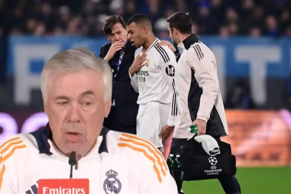 A soccer coach at a press conference while a player is assisted by medical staff on the field.