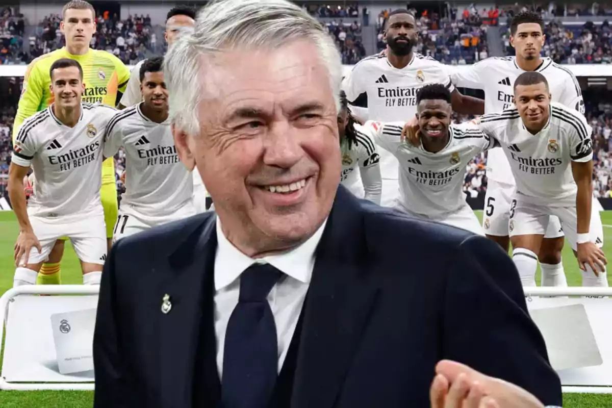 Un grupo de jugadores de fútbol con uniforme blanco posando en el campo, con un hombre mayor sonriendo en primer plano.