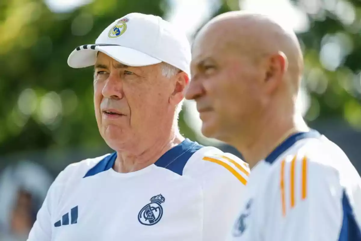 Two men wearing Real Madrid sportswear, one wearing a white cap, in an outdoor setting.