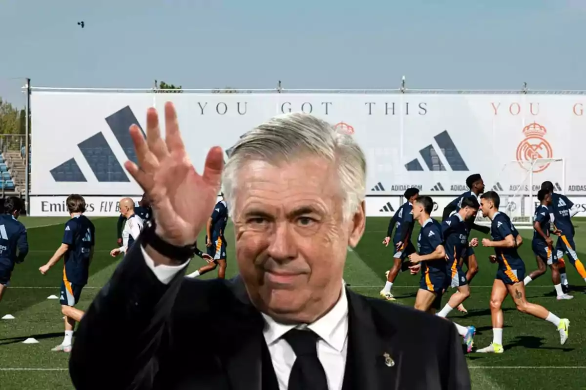 A soccer coach waves while his players train on the field.