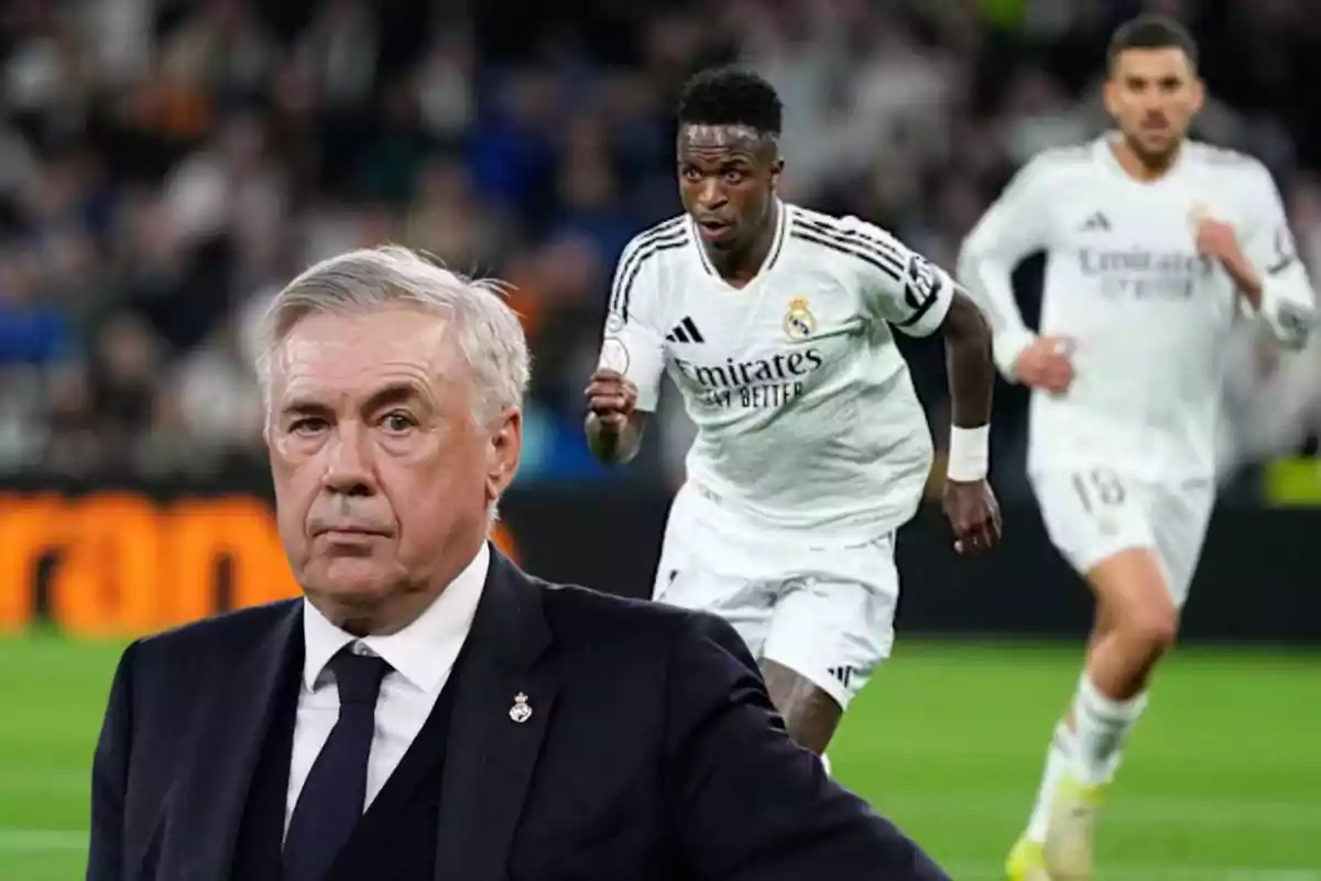 A soccer coach in the foreground with two Real Madrid players running on the field during a match.