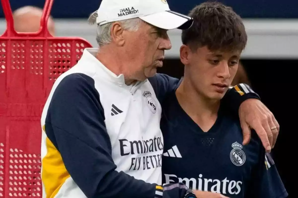 A soccer coach in a white cap hugs a young player as they talk on the field. A soccer coach in a white cap hugs a young player as they talk on the field.
