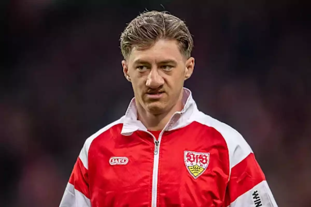 Soccer player wearing a red and white Stuttgart jacket in a stadium