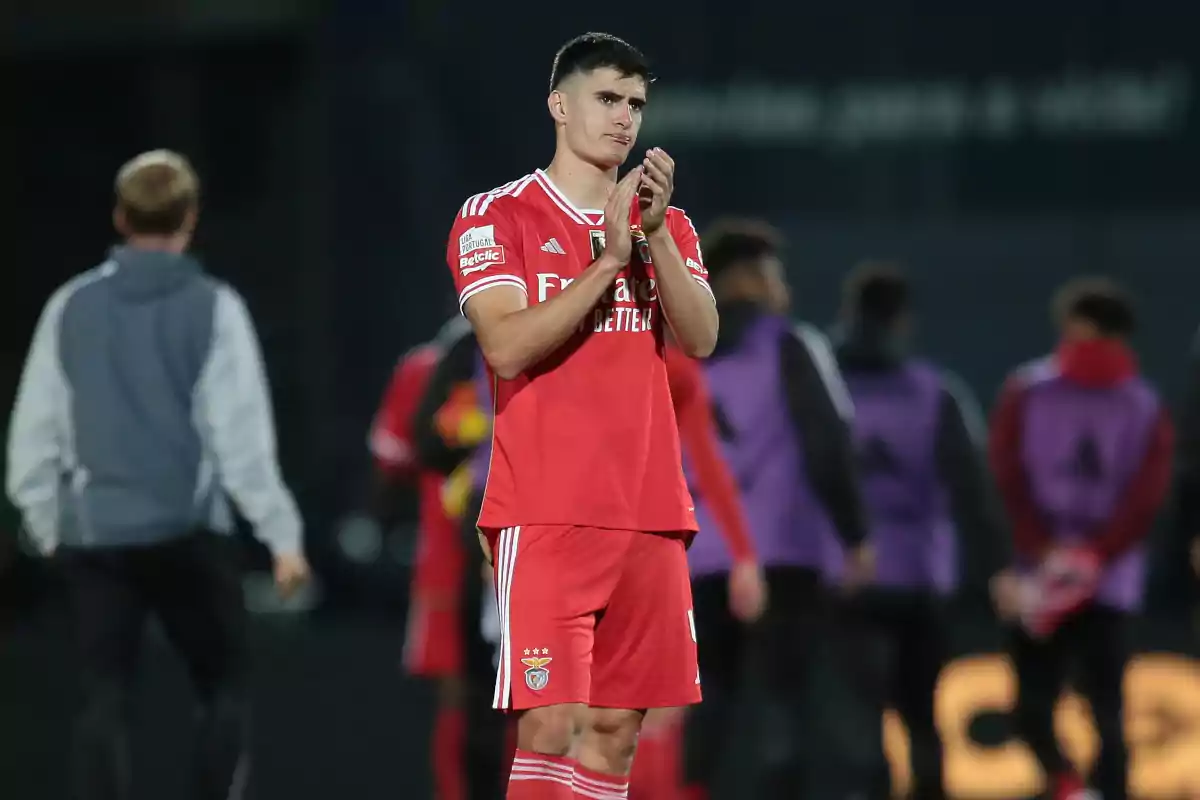 A soccer player in a red uniform applauds on the field after a game. A soccer player in a red uniform applauds on the field after a game.