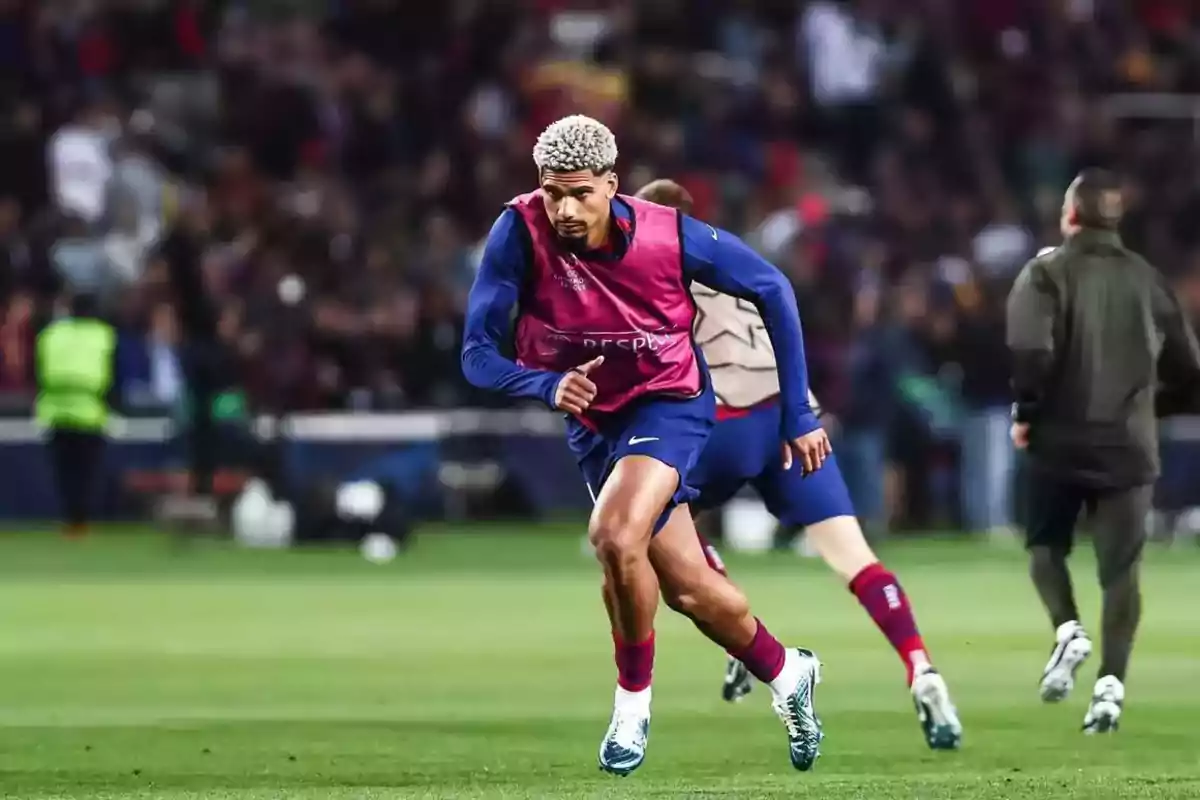 A soccer player in a pink vest runs on the field during a warm-up, with the crowd in the background. A soccer player in a pink vest runs on the field during a warm-up, with the crowd in the background.