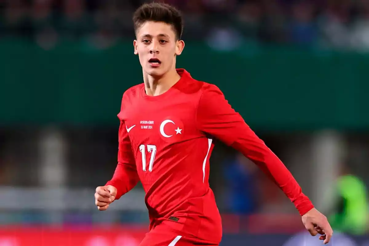 Jugador de fútbol con uniforme rojo de Turquía en acción durante un partido.