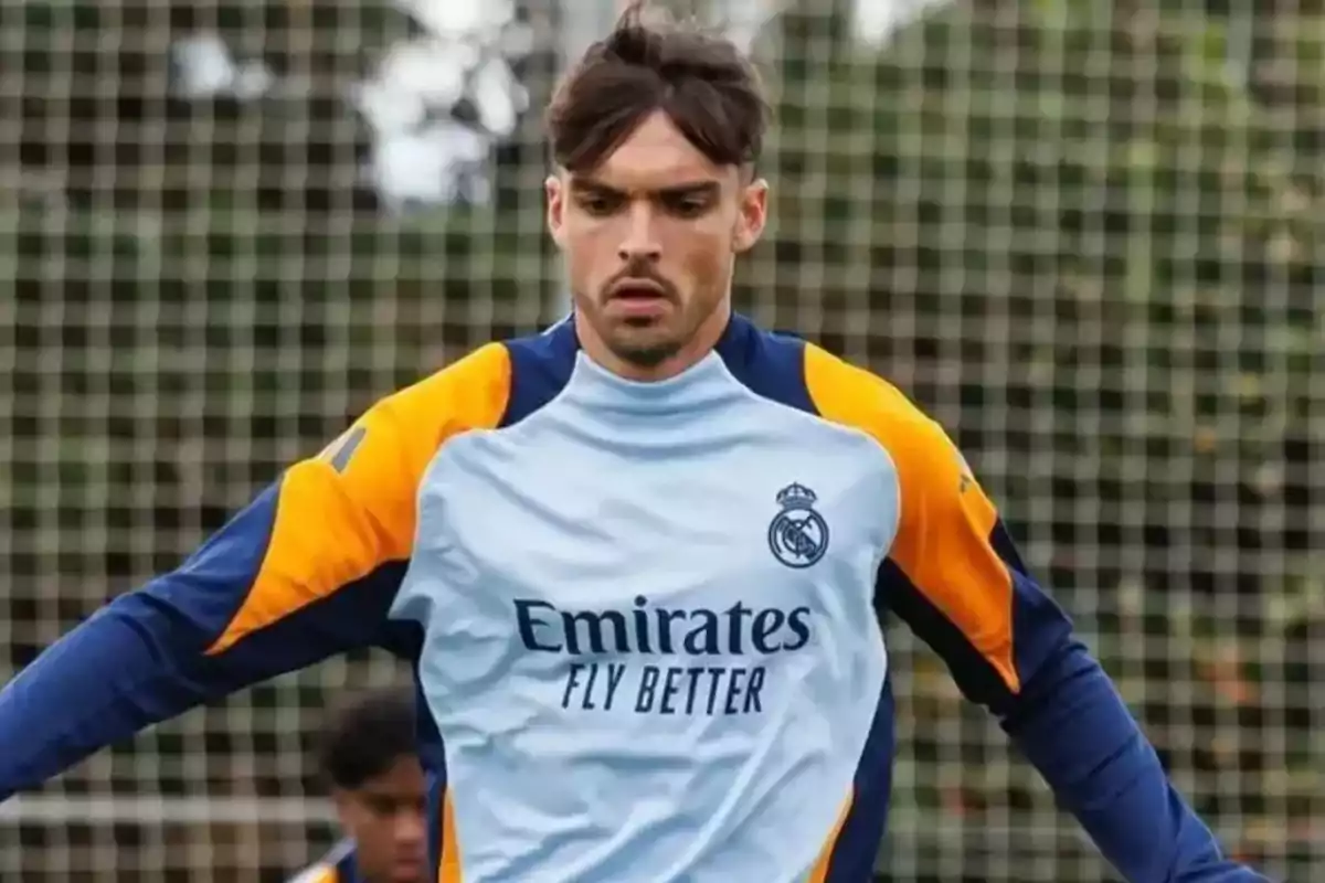 A soccer player in a Real Madrid training uniform on the field.