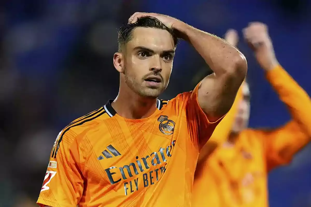 Soccer player in orange Real Madrid uniform on the field with surprised expression. Soccer player in orange Real Madrid uniform on the field with surprised expression.