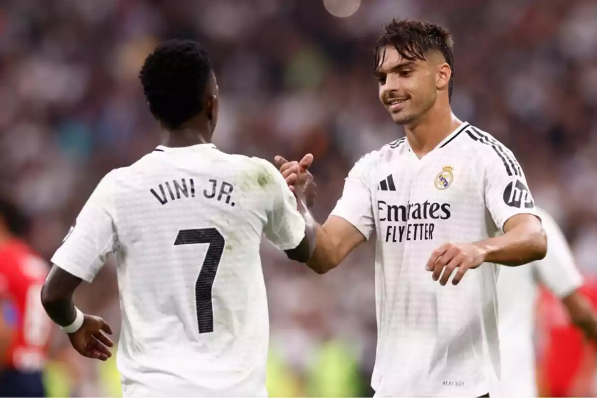 Dos jugadores de fútbol del Real Madrid celebran en el campo.