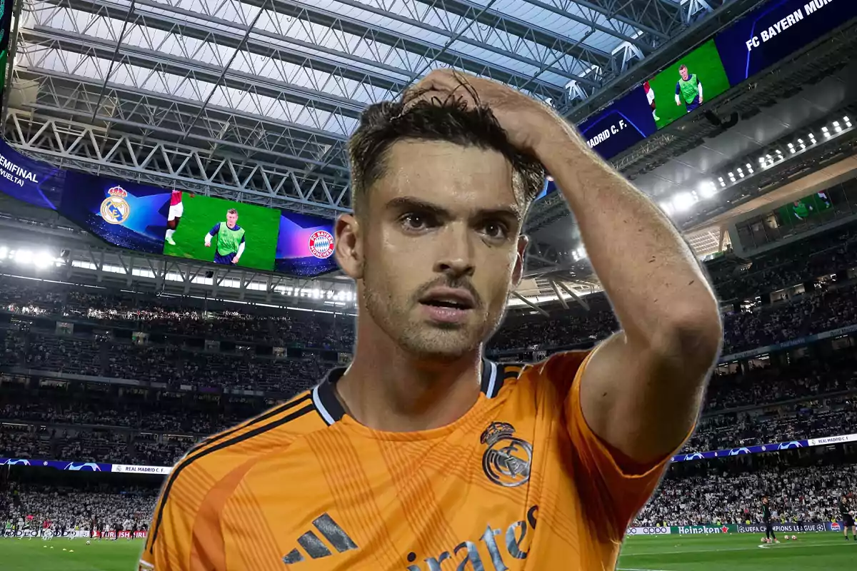 Futbolista con uniforme naranja del Real Madrid en un estadio lleno de aficionados con pantallas gigantes al fondo mostrando imágenes del partido
