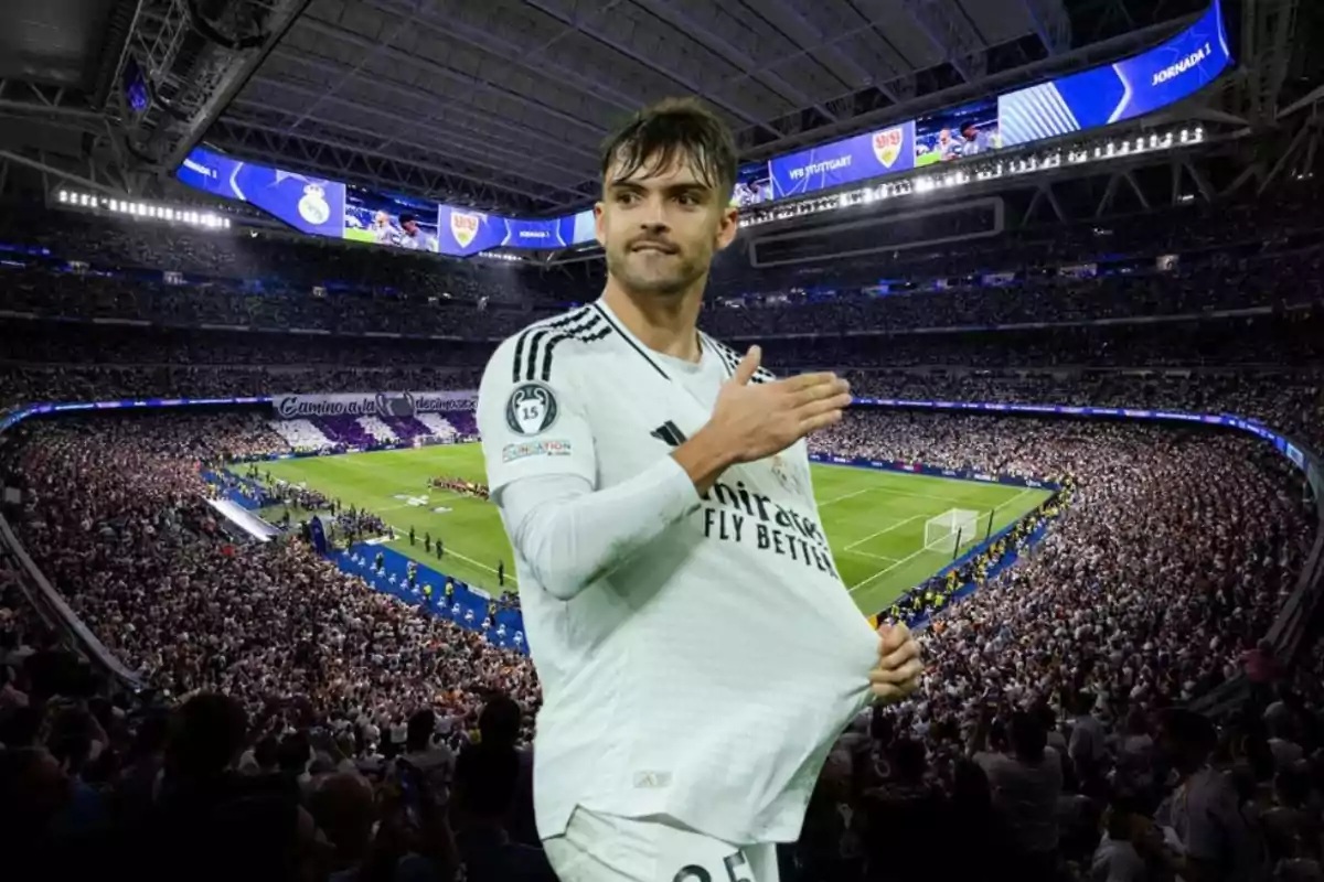 Un jugador de fútbol en uniforme blanco celebra en un estadio lleno de espectadores.