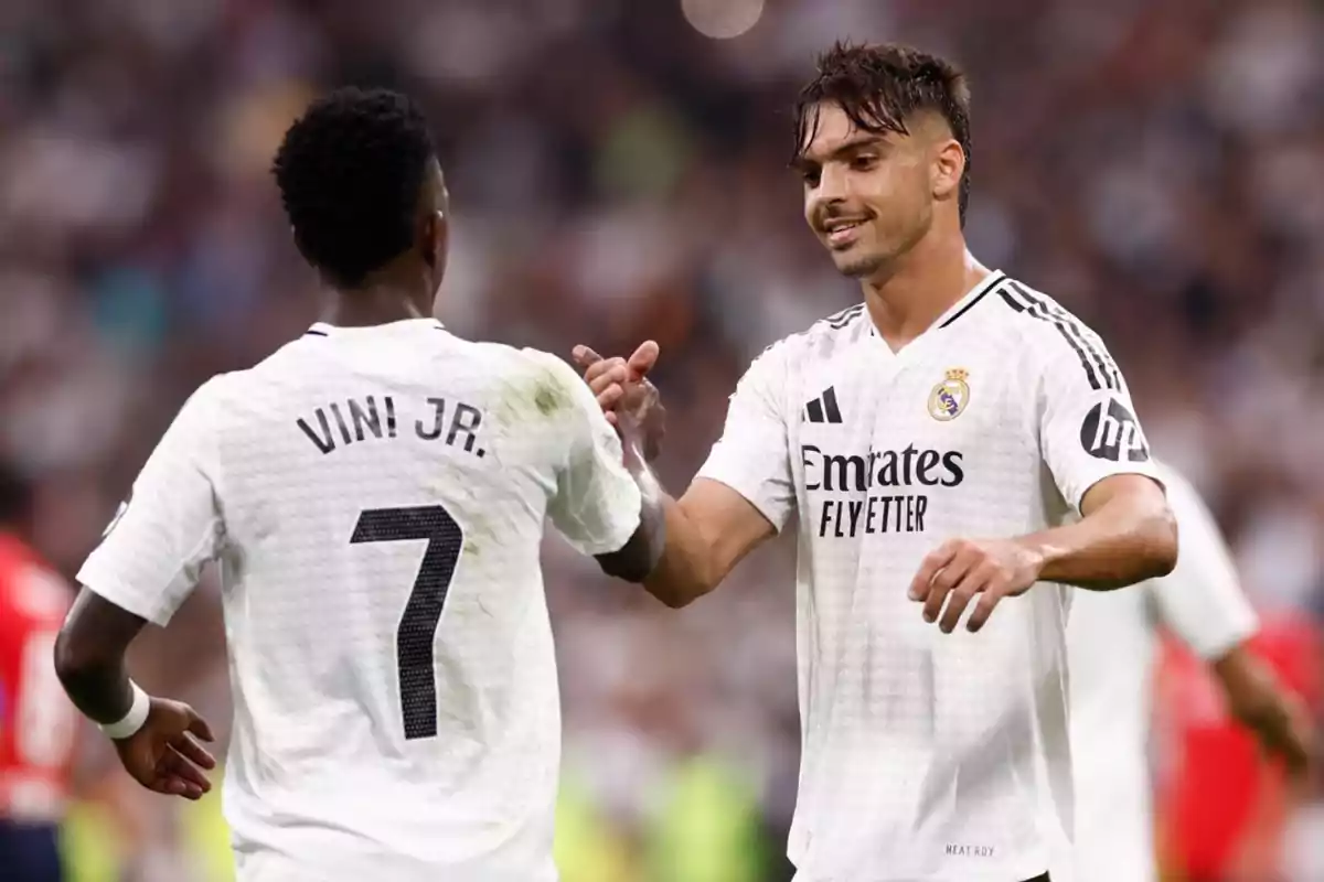 Dos jugadores de fútbol del Real Madrid celebran en el campo con un apretón de manos. Dos jugadores de fútbol del Real Madrid celebran en el campo con un apretón de manos.