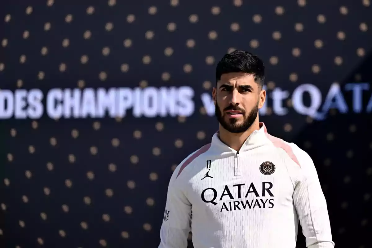 A soccer player in a PSG uniform in front of a dark background with blurred text. A soccer player in a PSG uniform in front of a dark background with blurred text.