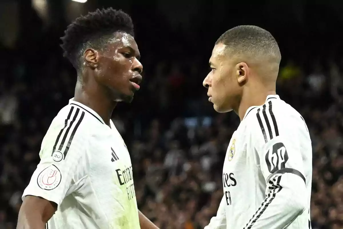 Dos futbolistas con uniforme blanco del Real Madrid se miran de cerca en el campo durante un partido Dos futbolistas con uniforme blanco del Real Madrid se miran de cerca en el campo durante un partido