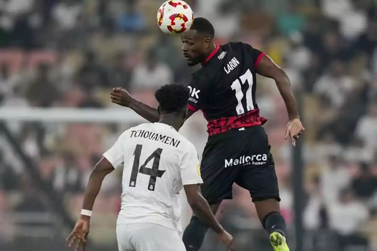 Two soccer players compete for a ball in the air during a game. Two soccer players compete for a ball in the air during a game.