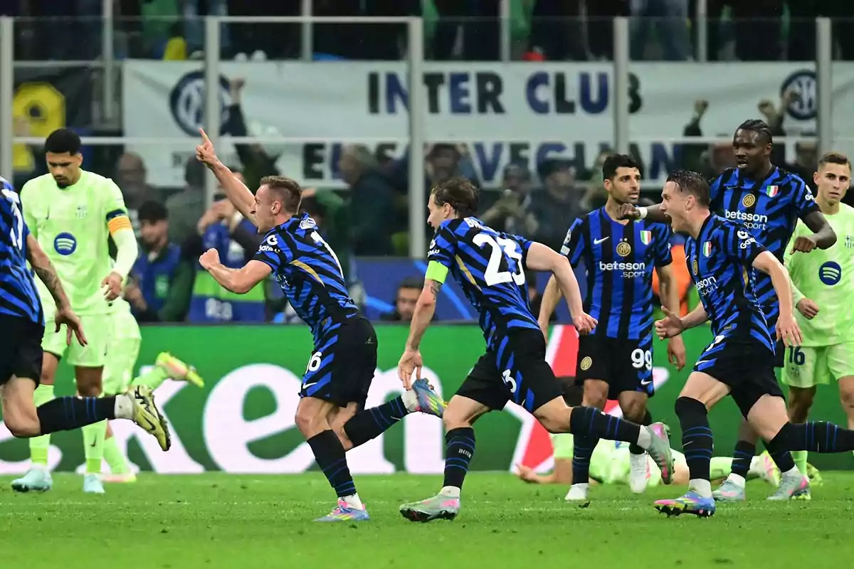 Jugadores de fútbol con uniforme azul y negro celebran en el campo mientras otros jugadores con uniforme verde observan. Jugadores de fútbol con uniforme azul y negro celebran en el campo mientras otros jugadores con uniforme verde observan.