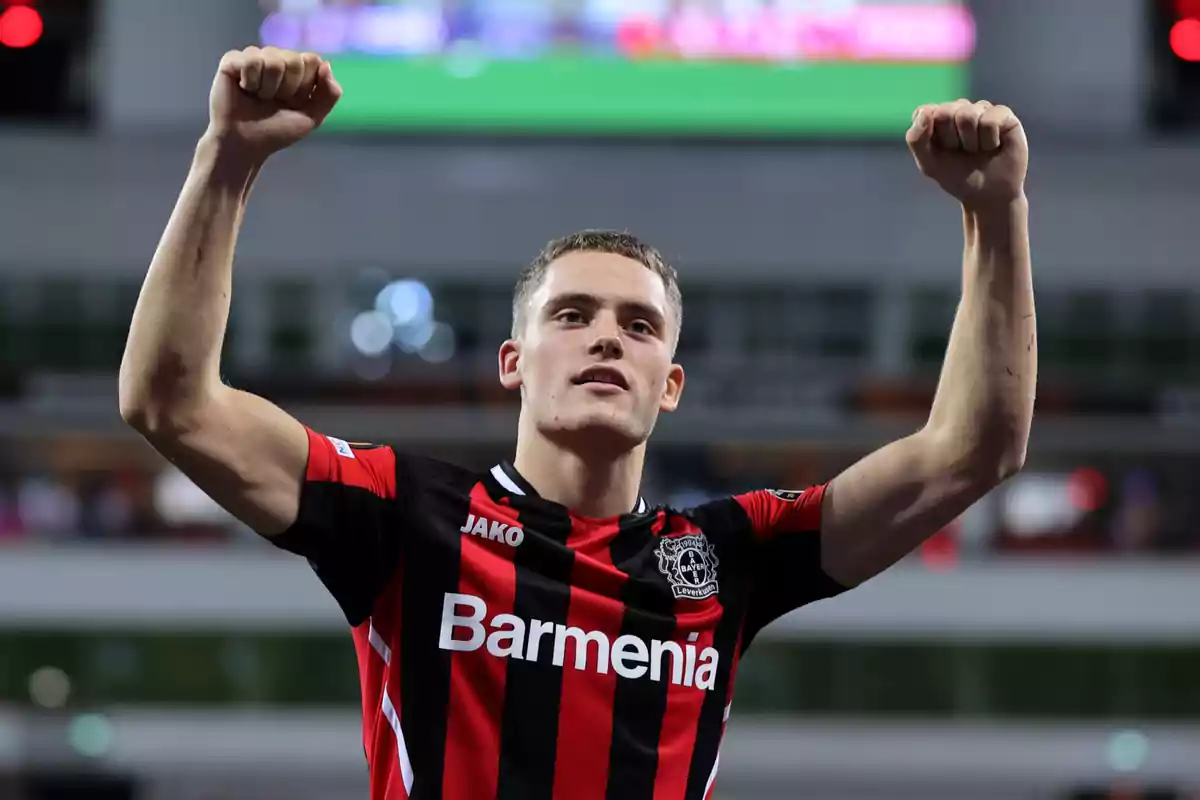 Jugador de fútbol celebrando con los brazos en alto vistiendo la camiseta del Bayer Leverkusen.