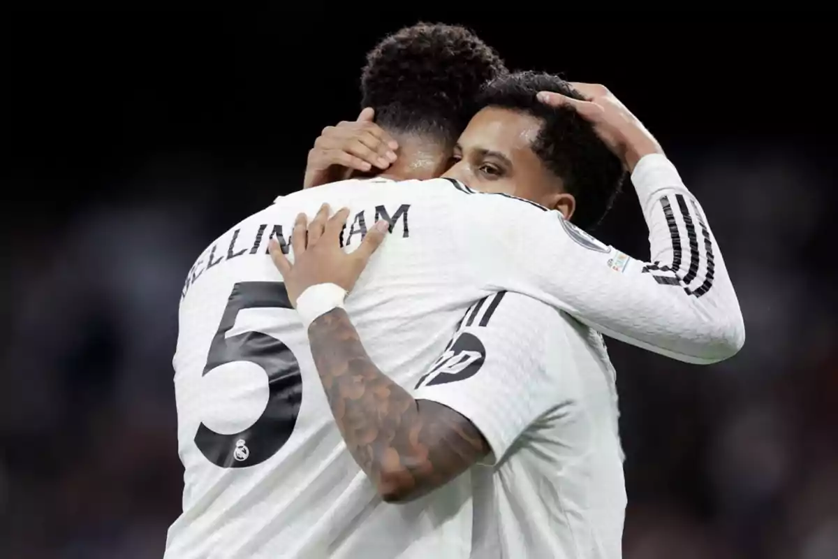 Two soccer players hugging on the field in white jerseys. Two soccer players hugging on the field in white jerseys.
