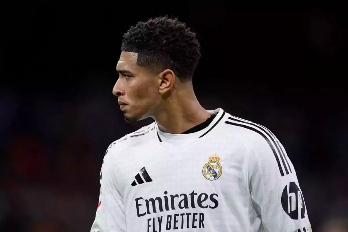 Jugador de fútbol con uniforme blanco del Real Madrid mirando hacia la izquierda.