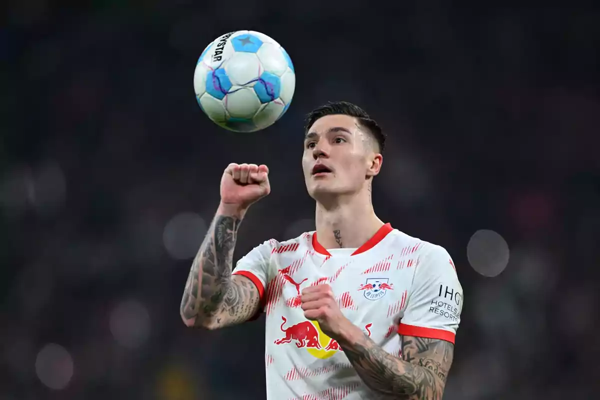 Futbolista con uniforme blanco y rojo del RB Leipzig lanzando un balón durante un partido Futbolista con uniforme blanco y rojo del RB Leipzig lanzando un balón durante un partido
