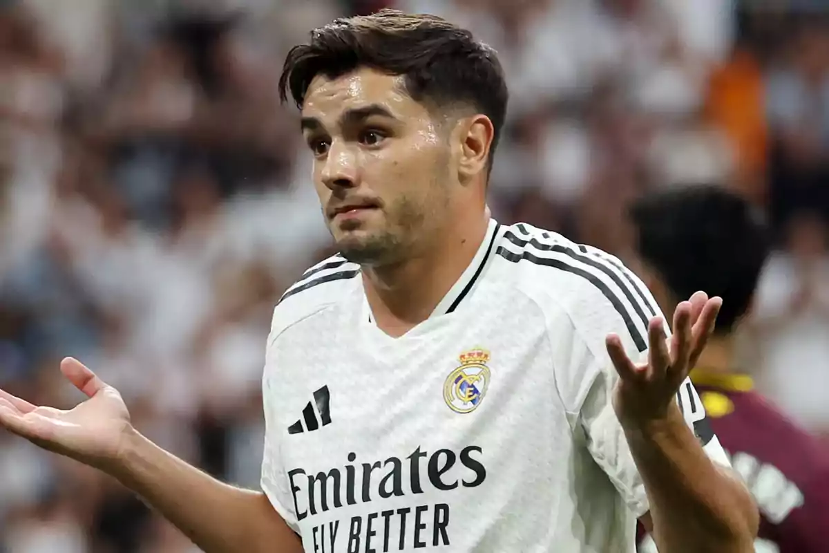 Soccer player in white uniform making a confused gesture on the field.