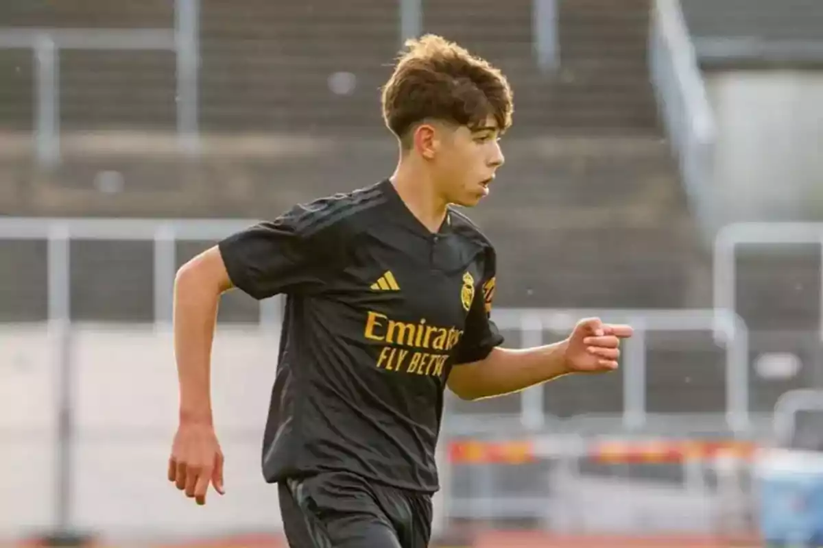 Un joven futbolista con uniforme negro corre en un campo de fútbol. Un joven futbolista con uniforme negro corre en un campo de fútbol.
