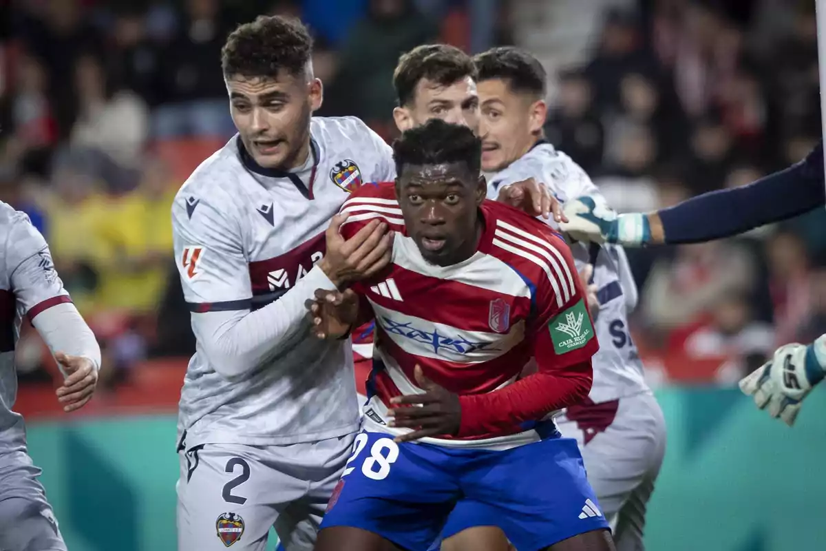 Soccer players from two different teams tussle during a match as they try to gain position in the box. Soccer players from two different teams tussle during a match as they try to gain position in the box.