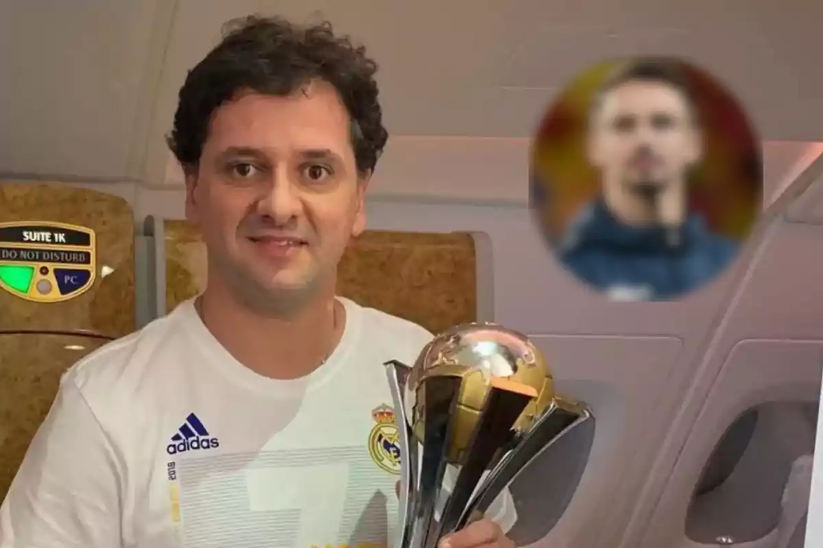 Un hombre con una camiseta del Real Madrid sostiene un trofeo dentro de un avión.