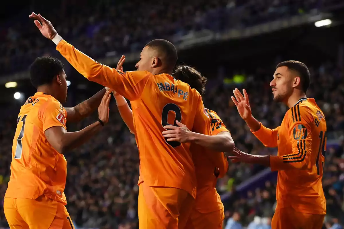 Jugadores de fútbol con uniformes naranjas celebrando en el campo.