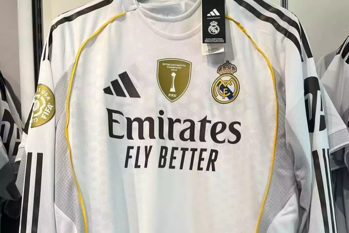 White Real Madrid jersey with yellow details, club crest, Adidas logo, Emirates Fly Better sponsorship, and FIFA championship patches.