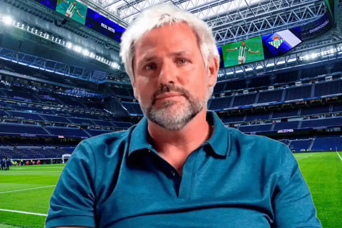 Hombre de cabello canoso y barba en un estadio de fútbol vacío.