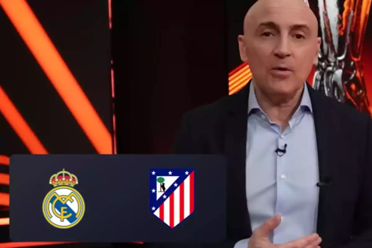 Un hombre en un estudio de televisión con los logos de dos equipos de fútbol en la pantalla.