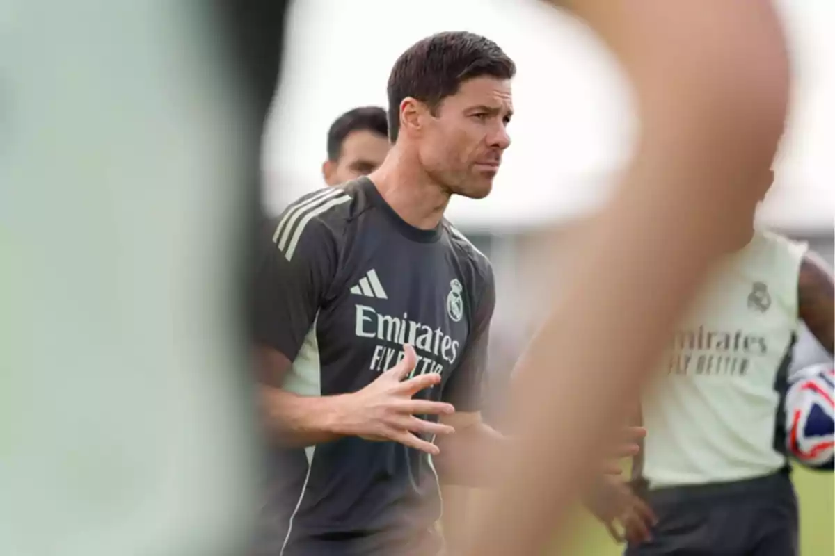 Soccer coach giving instructions during a practice with Real Madrid players in the background