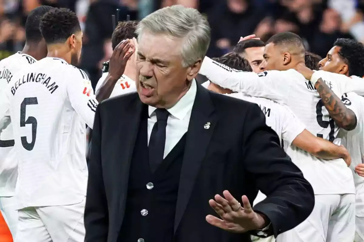 A soccer coach gestures while a group of players celebrates in the background.