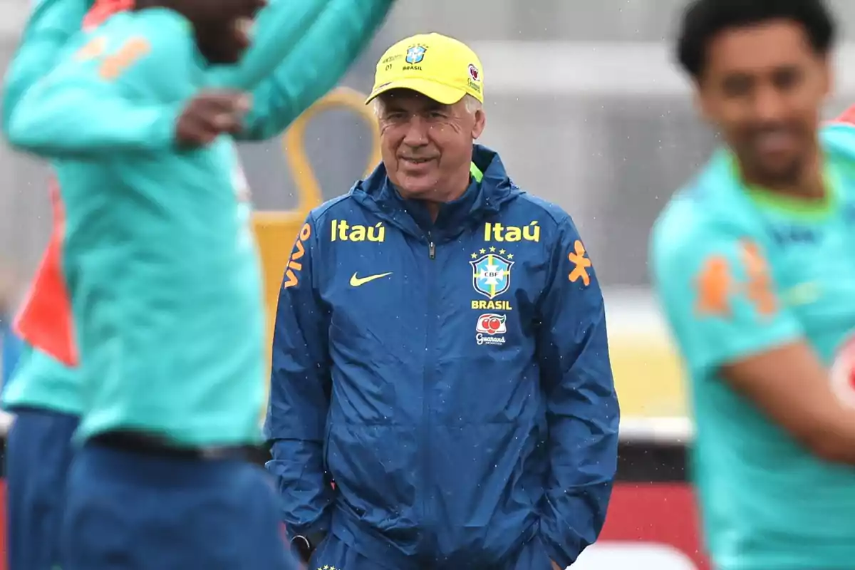 Brazil's national soccer team coach smiles during a training session in the rain as players practice around him.