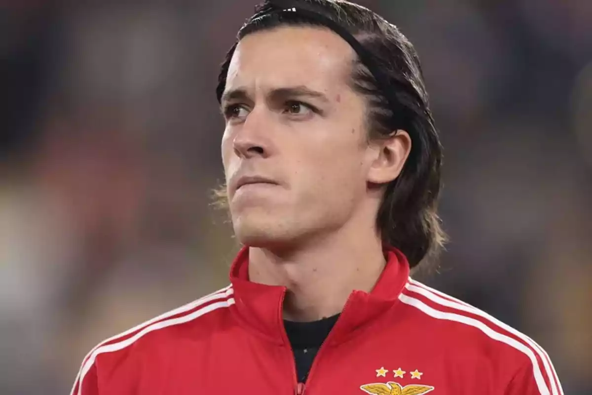 A player with a headband and a red jacket with a team crest. A player with a headband and a red jacket with a team crest.