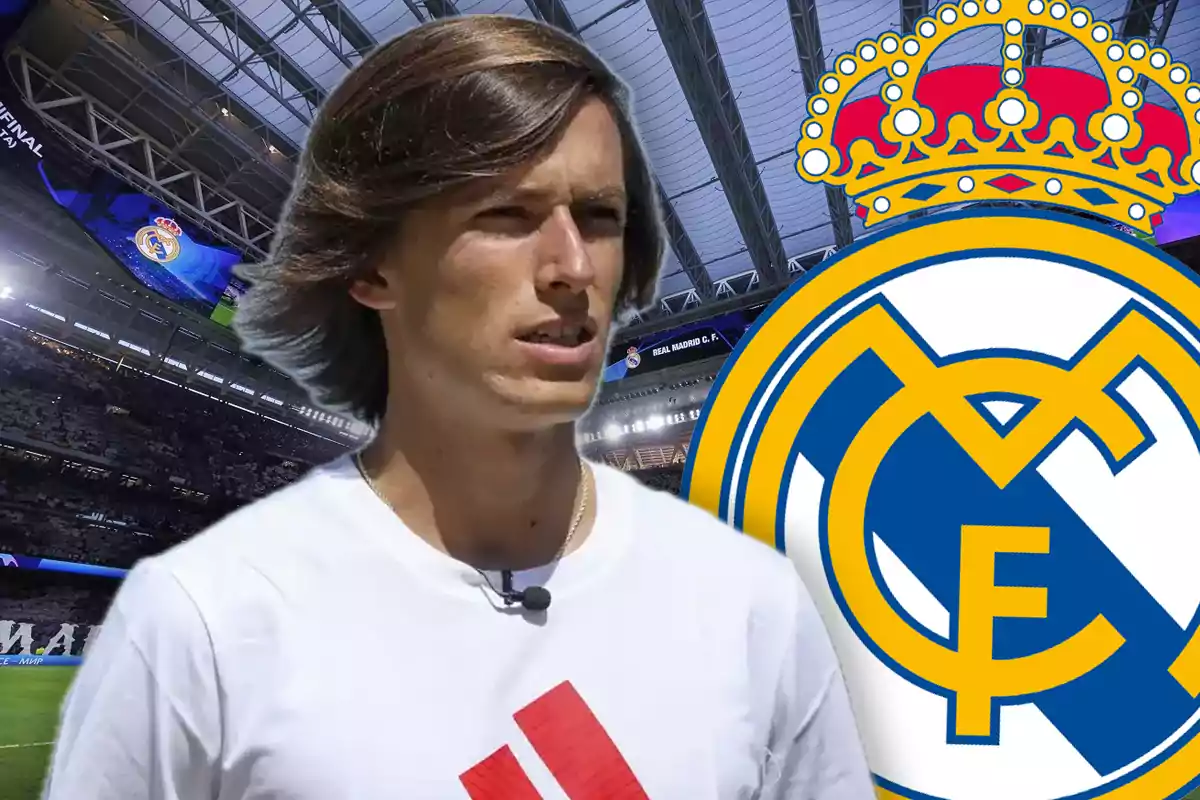 Joven con camiseta blanca frente al escudo del Real Madrid en un estadio de fútbol cubierto