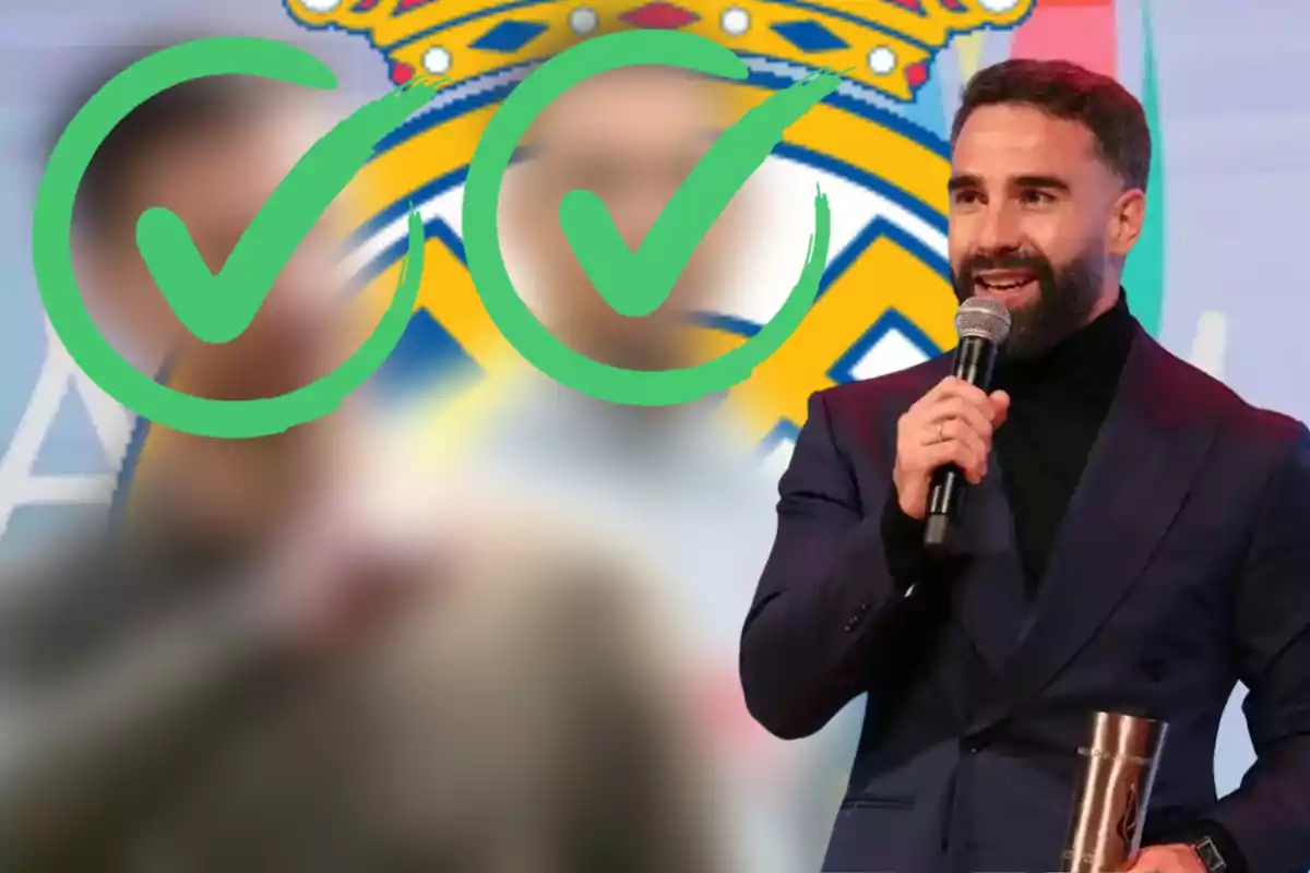 Un hombre con barba y traje oscuro sostiene un micrófono y un trofeo mientras habla en un evento con un fondo borroso y dos marcas de verificación verdes.