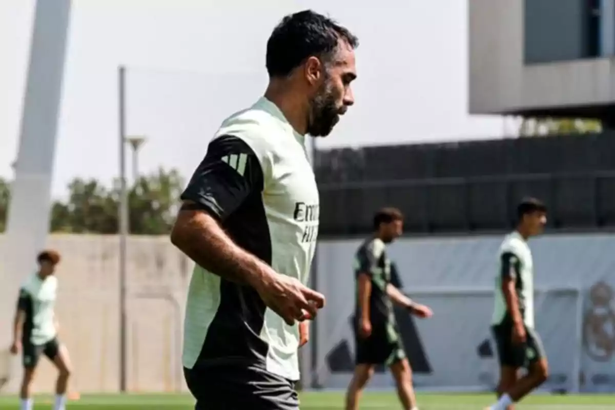 Futbolista entrenando en un campo de fútbol con otros jugadores al fondo