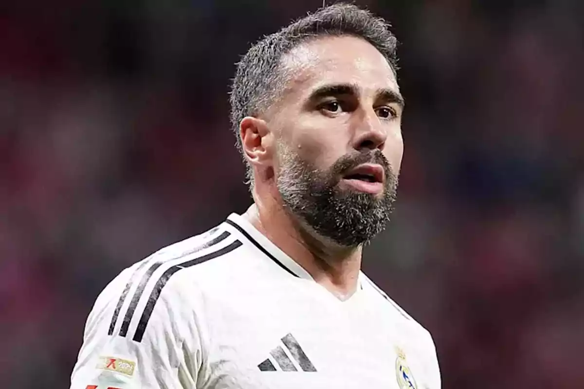A player with a beard and short hair is wearing a white jersey with black details.