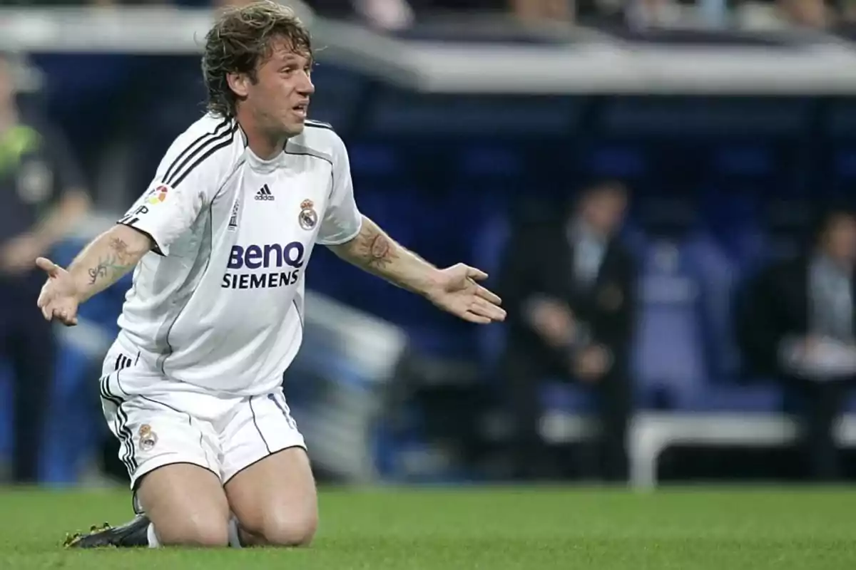 A Real Madrid soccer player kneeling on the field with his arms outstretched during a match. A Real Madrid soccer player kneeling on the field with his arms outstretched during a match.