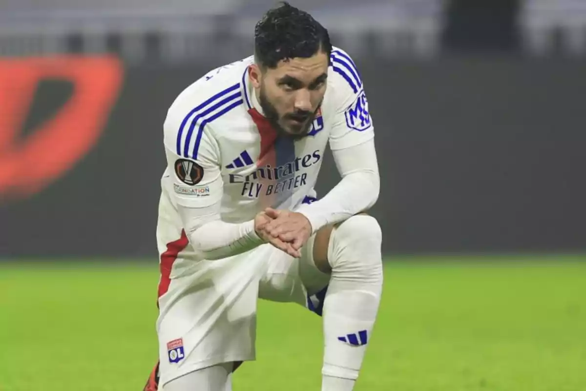 Un jugador de fútbol del Olympique de Lyon se agacha en el campo durante un partido.