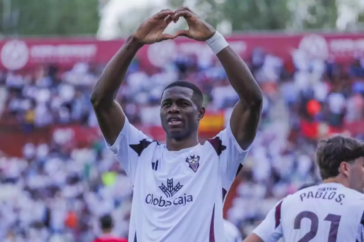 Futbolista celebrando un gol haciendo un gesto de corazón con las manos en un estadio lleno de aficionados Futbolista celebrando un gol haciendo un gesto de corazón con las manos en un estadio lleno de aficionados