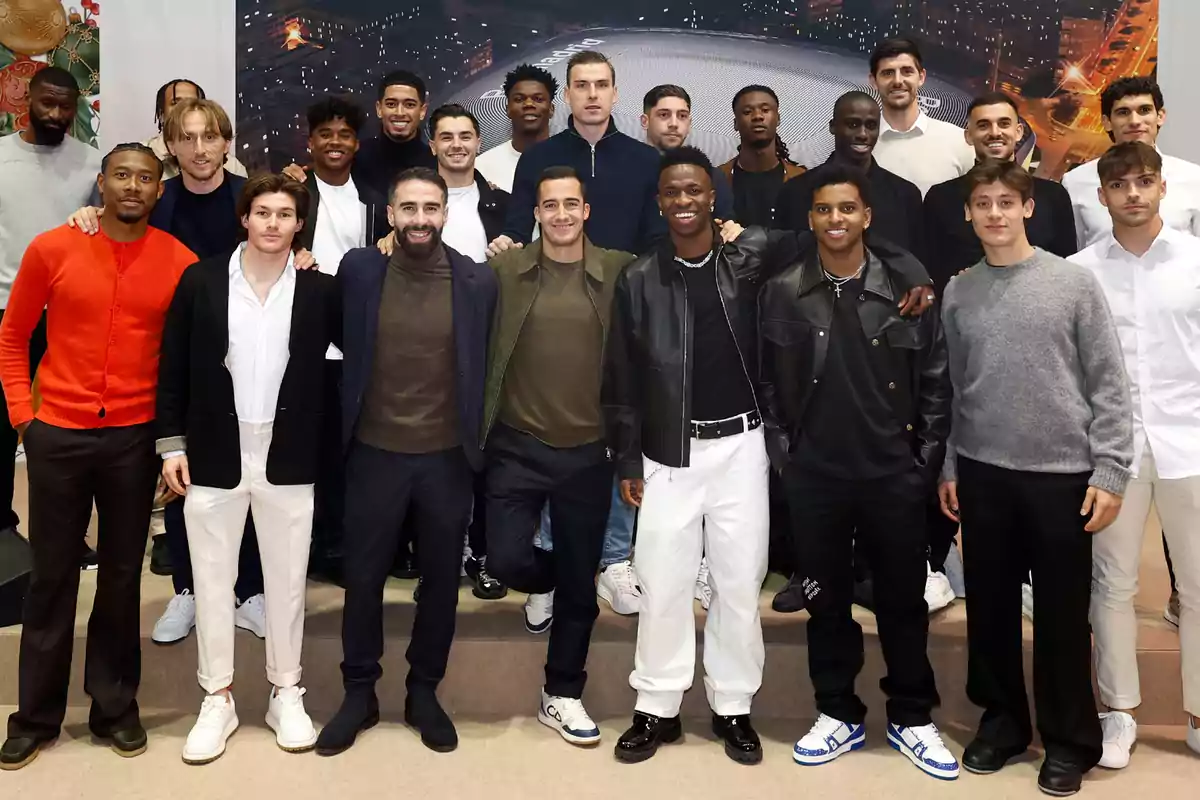 A group of people posing together, some of them smiling, in an indoor setting with a background that appears to be an image of a city lit up at night. A group of people posing together, some of them smiling, in an indoor setting with a background that appears to be an image of a city lit up at night.
