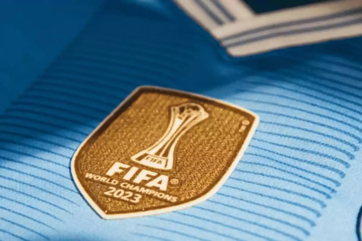 Escudo dorado de la FIFA 2023 sobre una camiseta azul.