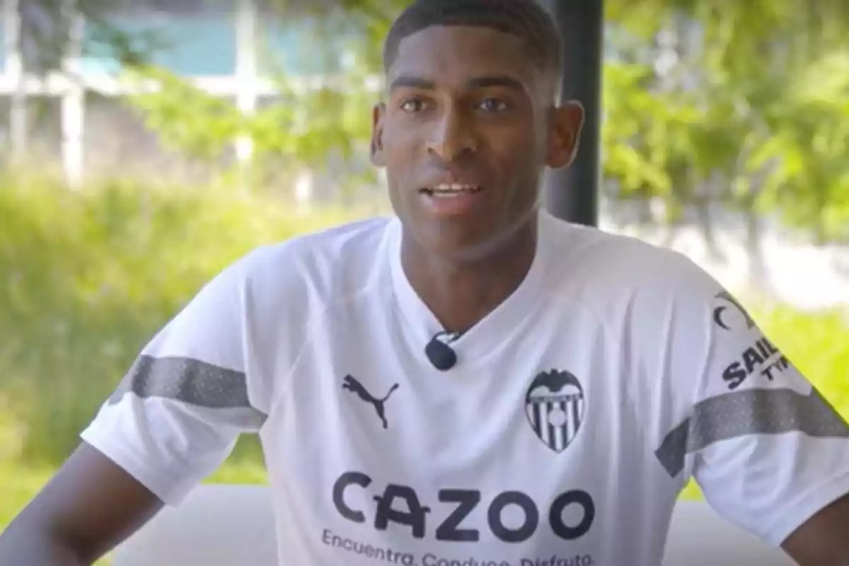 Un hombre con una camiseta blanca del Valencia CF hablando frente a un fondo verde. Un hombre con una camiseta blanca del Valencia CF hablando frente a un fondo verde.